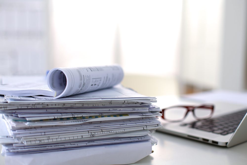 stack of papers on table with computer in background