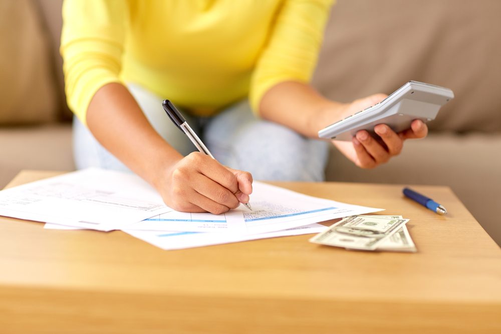 woman writing budget and holding calculator
