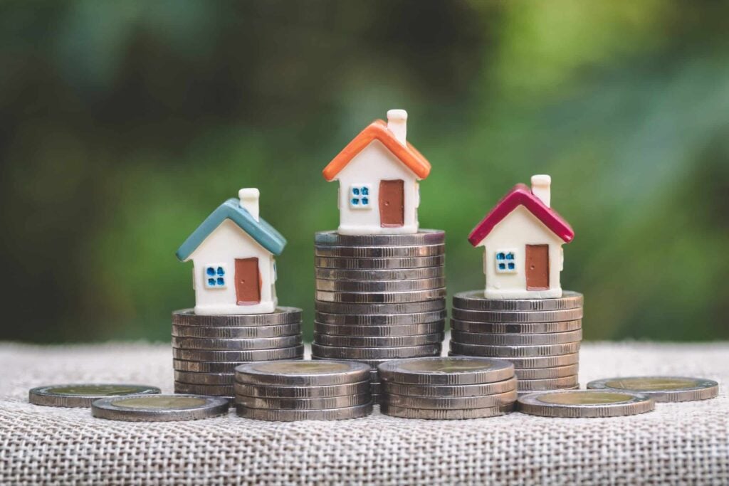 small house figures sitting on stacked coins