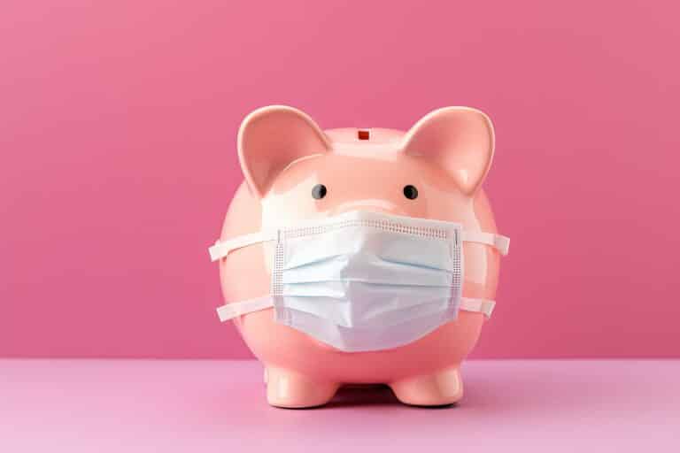 Men holding money in a piggy bank on a pink background representing savings or financial crisis after COVID 19