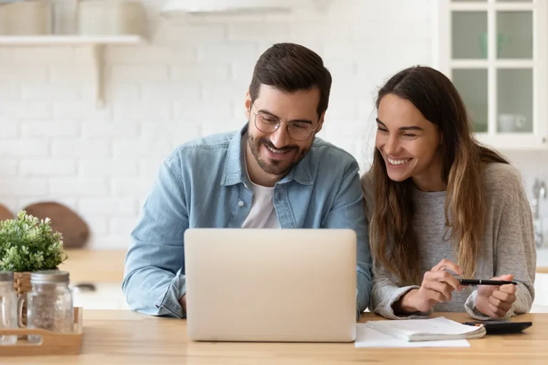 man and woman smiling looking at laptop