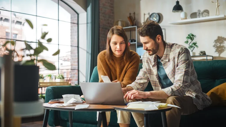 a man and woman looking at laptop and papers discussing debt relief