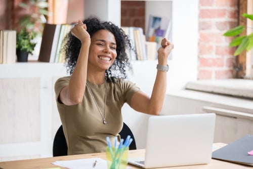woman sitting down with arms in the air and showing excitement
