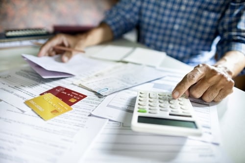 papers and credit cards laying on table. someone calculating payments using calculator