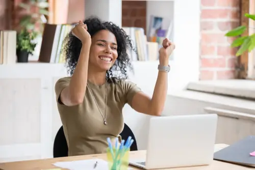 woman sitting down with arms in the air and showing excitement