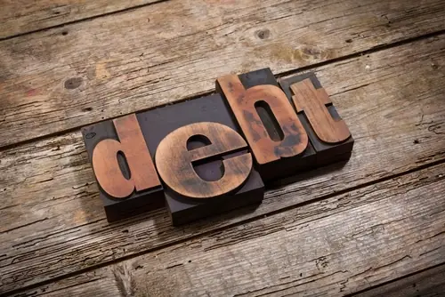 image of word "debt" with wood backdrop
